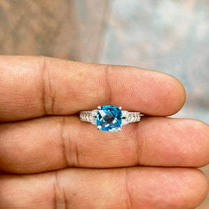 Elegant 2.12 Ct AAA Swiss Blue Topaz ring with cushion checkerboard cut, accented by 0.04 Ct round diamonds in 14K white gold. Antique-inspired filigree design with rhodium finish, 2.0–2.5 mm band, perfect for women seeking timeless sophistication, vintage charm, and luxurious everyday or evening wear jewellery. 