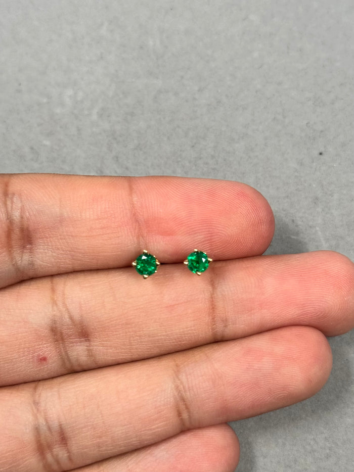 Elegant 0.42–0.55 Ct natural emerald stud earrings in 18K yellow gold. 4mm round AA green gemstones in a timeless scroll design for women