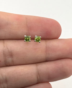 Side view of the natural peridot stud showing the scroll profile and 14K white gold surface 