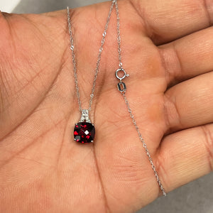 Elegant 2.50 Cts cushion checkerboard garnet filigree pendant crafted in 14K white gold, accented with 0.04 Cts round brilliant diamonds. The deep red AAA garnet centerpiece radiates rich colour and brilliance, suspended from an 18-inch Singapore chain. A refined women’s jewellery piece combining vintage filigree detail with modern luxury styling. 