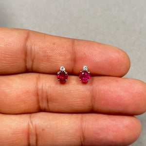 Elegant ruby and diamond stud earrings crafted in 18K white gold with a rhodium finish, featuring 1.18 carats of natural round rubies and 0.06 carats of sparkling diamonds. The prong-set gemstones enhance brilliance while the secure screw-back closure ensures comfort. A timeless women’s fine jewellery piece perfect for adding vibrant red colour and refined sophistication. 