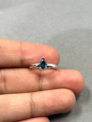 Pear-shaped 0.53 Ct teal blue diamond solitaire ring in 14K white gold with rhodium finish, prong setting, slim 2.3–2.4 mm band, SI quality natural treated diamond, ring size 4, elegant minimalist fine jewelry design. 
