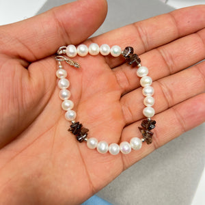 8 inch sterling silver bracelet featuring white Akoya cultured pearls paired with natural AA Smokey Quartz chip beads. Strung in a continuous design, this women’s bracelet showcases soft pearl lustre against medium brown quartz tones. Finished with a secure lobster clasp, offering a lightweight, smooth, and balanced look suitable for everyday wear and layered styling.