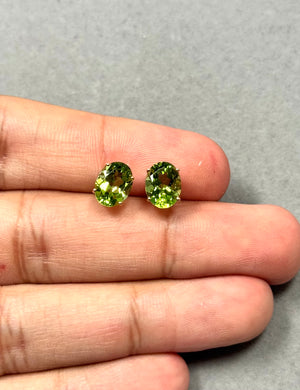 Oval Peridot stud earrings in solid 14K yellow gold featuring two natural AAA quality gemstones (9x7 mm) with vivid medium green color. Four-prong set August birthstone earrings with secure push backs, elegant gemstone studs for women and everyday fine jewelry style. 