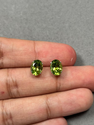 AAA natural oval Peridot stud earrings set in solid 14K white gold, featuring two radiant 9x7 mm gemstones with a total weight of 3.86–4.06 carats. These prong-set green peridot earrings offer a bright medium-green sparkle with secure push backs, designed for elegant everyday wear or refined evening jewelry styling. 