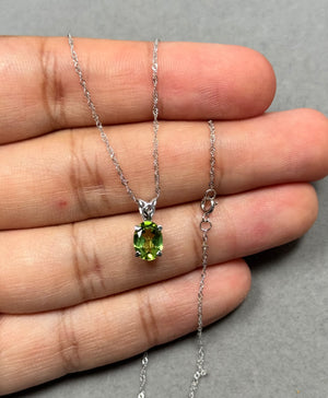 Natural oval peridot pendant in solid 14K white gold, featuring a 1.20–1.50 Ct AAA green gemstone in a classic prong setting. Finished with rhodium for extra shine and paired with an 18 inch Singapore chain, this elegant women’s necklace offers a fresh green glow, perfect for daily wear or refined evening styling. 