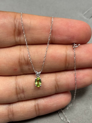 Natural AAA oval Peridot scroll pendant in solid 14K white gold, featuring a 0.40–0.60 ct medium green gemstone in a secure prong setting. Elegant scroll detailing enhances the refined design, paired with an 18-inch Singapore chain. A lightweight, polished necklace ideal for everyday wear, layering, or adding a subtle, sophisticated green accent. 