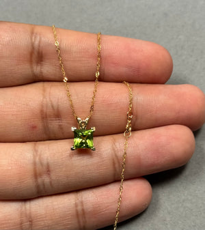 Princess-cut natural Peridot scroll pendant in solid 14K yellow gold, featuring a 0.95–1.50 Ct AAA gemstone with vivid medium green brilliance. Secure prong setting enhances clarity and sparkle, paired with an 18-inch Singapore chain. Elegant fine jewelry piece for women, designed with graceful scroll detailing and a polished gold finish for everyday wear or refined styling. 