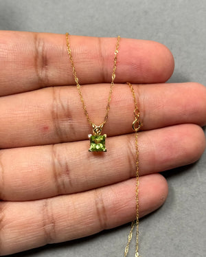 Princess-cut natural Peridot pendant in solid 14K yellow gold, featuring elegant scroll detailing and a vibrant medium-green AAA gemstone. This dainty necklace comes with an 18-inch Singapore chain, offering a refined, feminine look perfect for everyday wear or special occasions. 