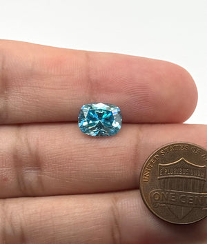 Lab created sea blue moissanite featuring a 10x8mm elongated cushion shape and eye clean clarity.