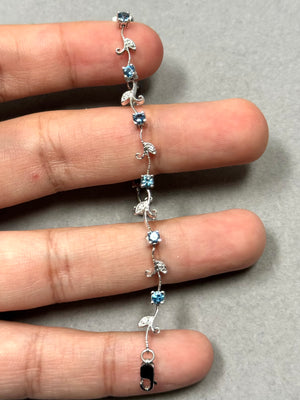 1.13 ct aquamarine and diamond bracelet in 14K white gold featuring a delicate bud and leaf design. Ten round AA aquamarines in soft light blue tones are paired with eleven prong-set diamonds, creating a balanced, elegant silhouette. Finished with rhodium plating and a secure lobster clasp, this 7-inch bracelet offers refined structure and everyday wearability. 