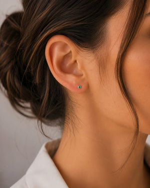 Women wearing a Petite emerald stud earrings worn on ear for elegant everyday jewelry styling