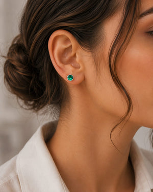 Woman wearing emerald stud earrings styled for elegant everyday jewelry inspiration