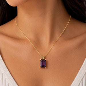  A gold chain necklace featuring a rectangular emerald-cut purple gemstone pendant held in a four-prong setting. 